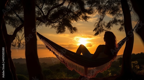 A girl is silhouetted in a hammock among trees while people are on vacation.