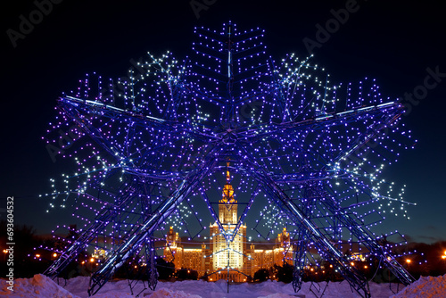 View of the Moscow State University building through a New Year's snowflake on New Year's Eve in the evening. Moscow, Russia