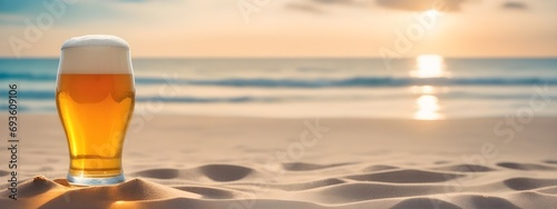 A glass of beer on the beach sand against the backdrop of the sea