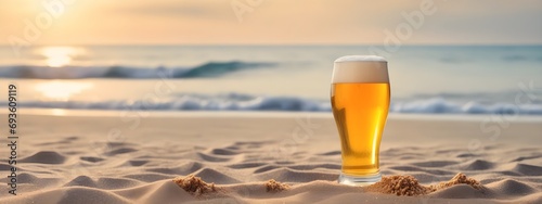A glass of beer on the beach sand against the backdrop of the sea
