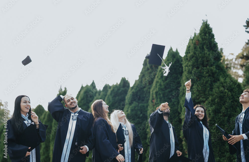 University students, in graduation gowns, celebrate in a park. They throw their caps in the air, sharing positive memories of their successful college journey.