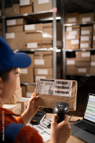 Warehouse worker scanning barcode on parcel using barcode scanner preparing parcels for shipment. photo