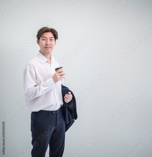 Business man portrait Asian one person wearing blue suit handsome smart standing looking  future success hand holding coffee cup paper ready for project work inside the office, with white background