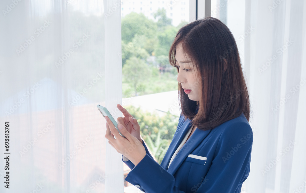 Business woman portrait Asian one person wearing blue suit, pretty girl cute smart looking, hand holding mobile phone and laptop check message ready for work inside the office, with white background Business woman portrait Asian one person wearing blue suit, pretty girl cute smart looking, hand holding mobile phone and laptop check message ready for work inside the office, with white background