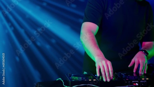 DJ's Hands Adjusting Sound Mixer Under Club Lights photo