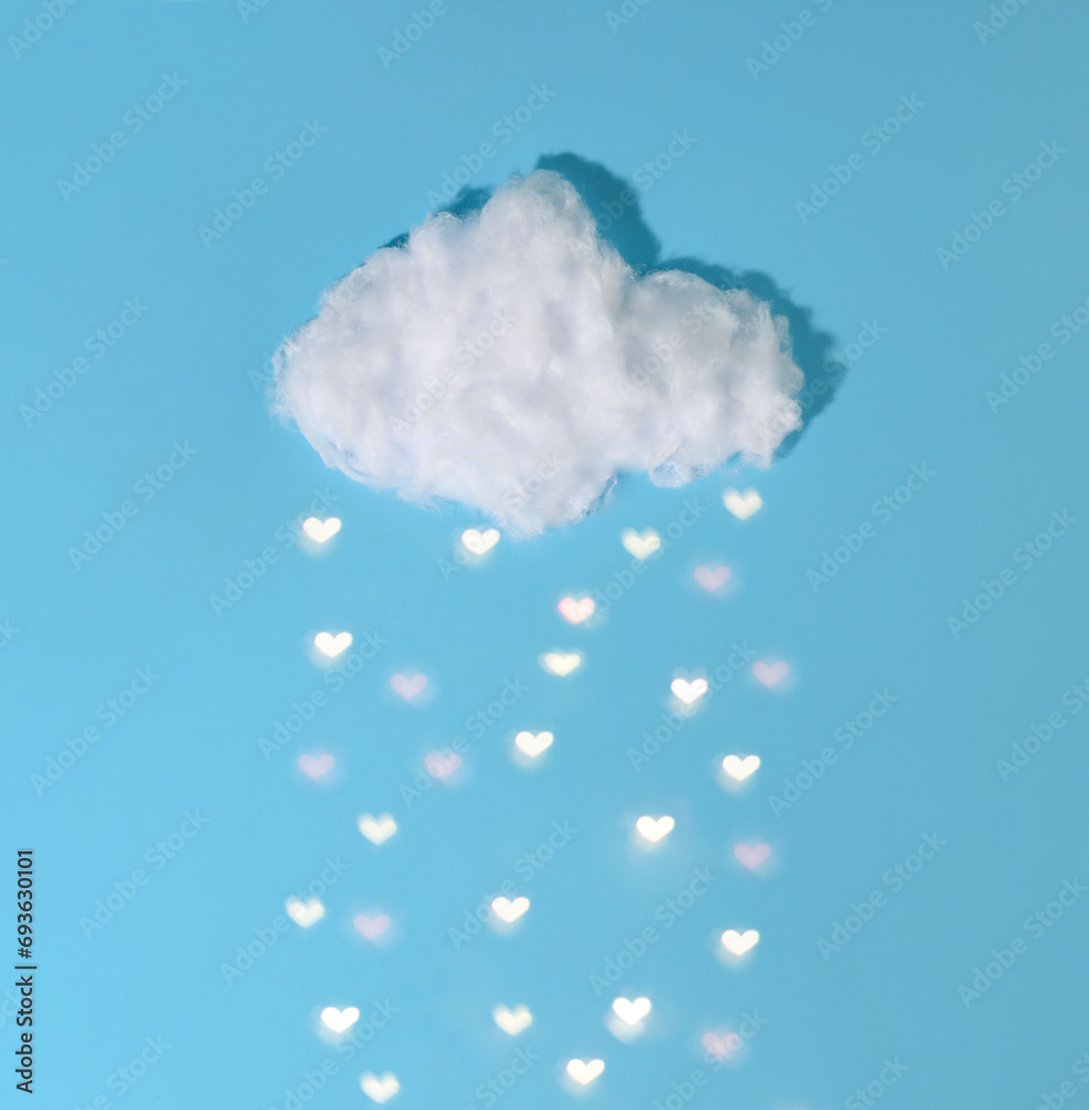 There is a white cloud on a blue background. hearts are falling from the cloud instead of drops