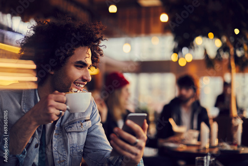 Smiling young man using smartphone in cafe photo