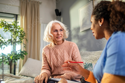 Senior woman talking to caregiver at home photo