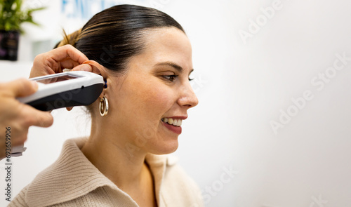 An unrecognizable ENT doctor uses a tympanometer in the ear of a pretty Caucasian girl to perform a hearing study. A device to detect alterations in the middle ear. Advertising in otolaryngology. photo