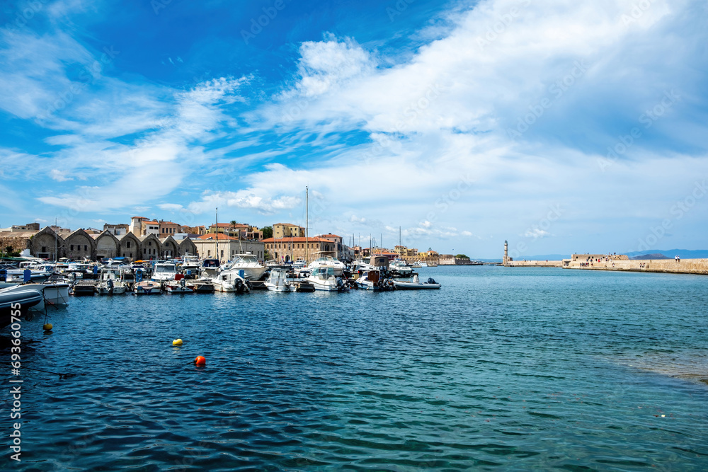Naklejka premium Venetian harbour in Old Town of Chania Crete Greece. Moored boat at marina, beacon, sea, blue sky.