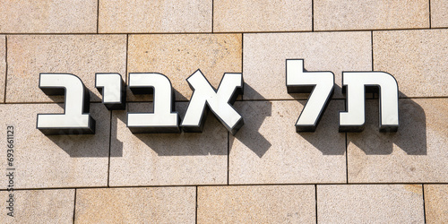Three-dimensional Hebrew letters on the tiled wall illuminated by the sun's rays and with shadows indicating the name of the city: Tel Aviv photo