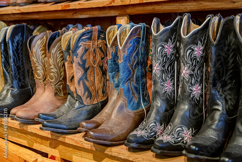 Cowboy boot on the shelf. American-style boots from ostrich and buffalo leather. Cowboy boot on the shelf. Shelves full of new cowboy boots. Aligned cowboys boots on a shelf in a store. photo