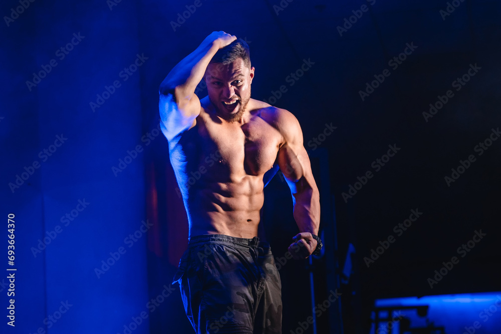 A Shirtless Man Commanding a Stage. A man without a shirt standing on a stage