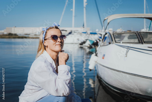 Woman in white shirt in marina , surrounded by several other boats. The marina is filled with boats of various sizes, creating a lively and picturesque atmosphere.