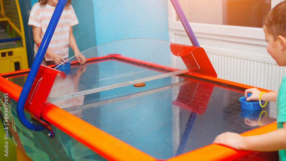 Naklejka premium Boy and girl friends play air hockey together in a children's entertainment center