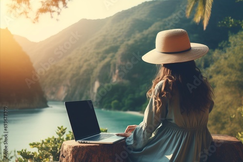 Young woman freelancer working online with laptop and enjoying stunning mountain landscape photo