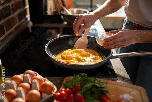 Woman hand Seasoning Scrambled Eggs on Stove in a Skillet