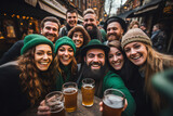 Happy people in St Patrick's Day outfits with beer taking selfie in city. St Patrick day. green beer and coins. Glasses of lager beer, a hat and coins with shamrock. 