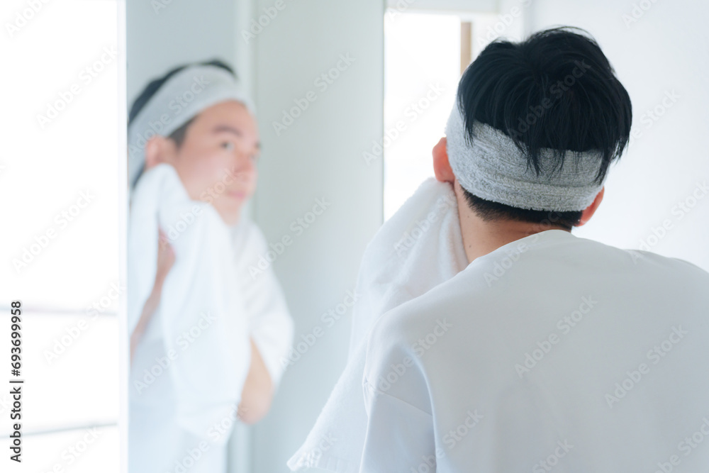 洗顔した顔をタオルで顔を拭く若い男性 洗顔した顔をタオルで顔を拭く若い男性