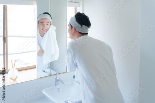 洗顔した顔をタオルで顔を拭く若い男性 photo