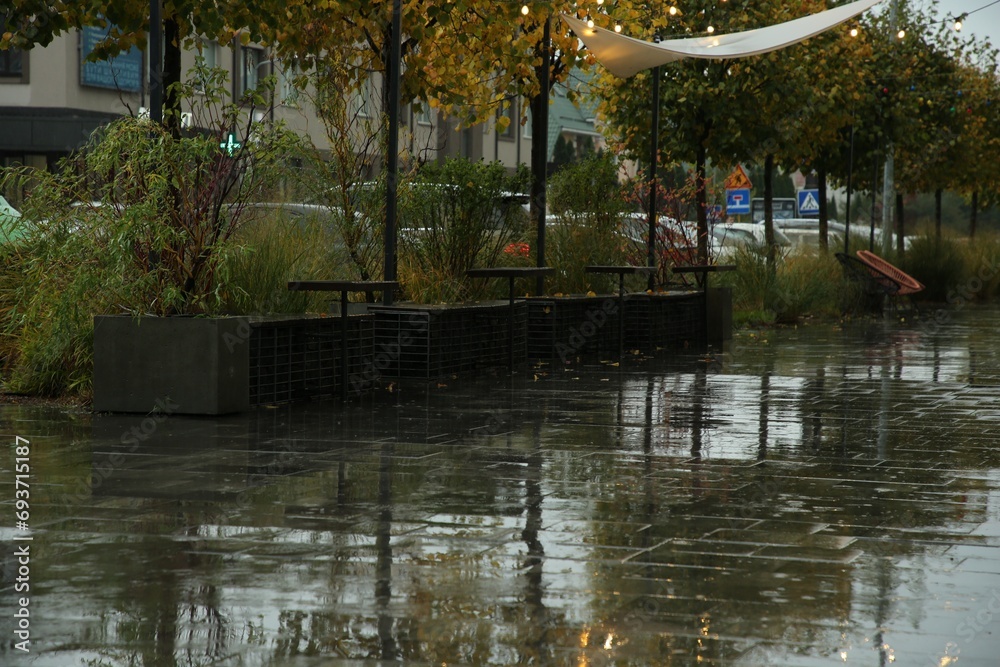Wet outdoor cafe furniture and puddles on pavement after rain Wet outdoor cafe furniture and puddles on pavement after rain