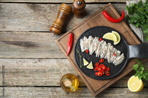 Tasty anchovies with spices and products on wooden table, flat lay. Space for text