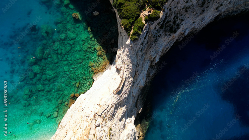 Aerial view of vertical cliff dividing turquoise blue transparent sea water