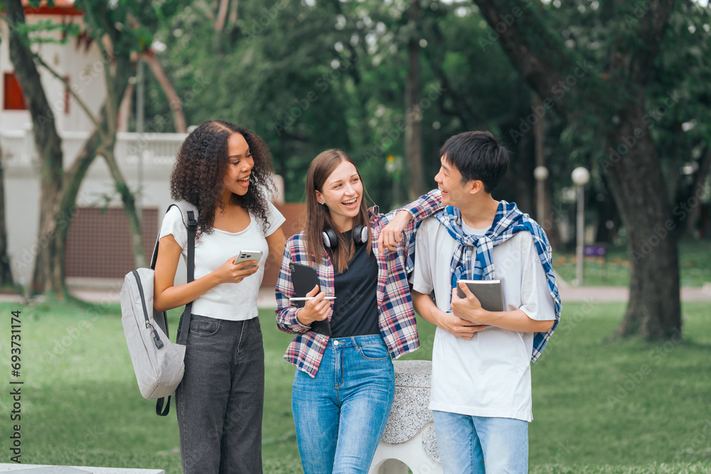 Group of young interracial diverse university students chatting together outside, engaging in a discussion together, college campus, enjoying campus recreation. Happy friends