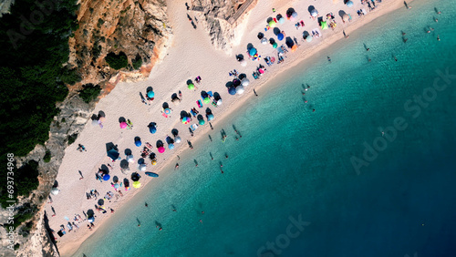 Aerial view of tropical beach with azure transparent sea water, sand, colorful umbrellas photo