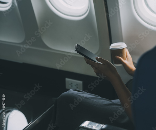 Asian woman enjoying enjoys a coffee comfortable flight while sitting in the airplane cabin, Passengers near the window.