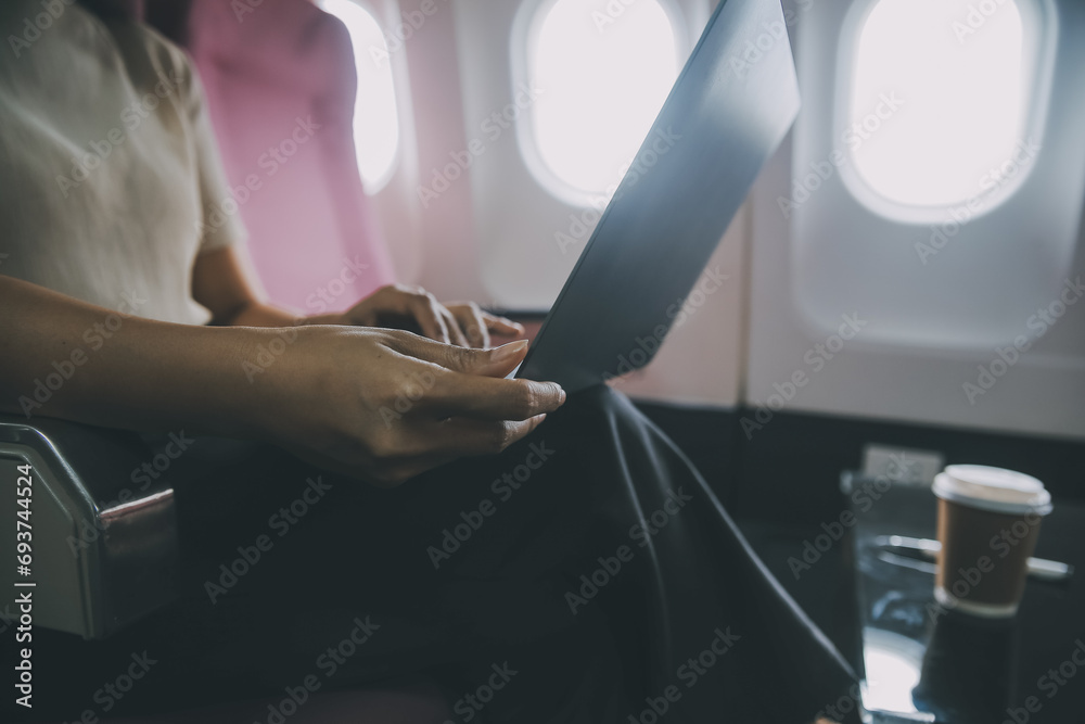 Asian woman passenger sitting in airplane near window and reading news from social networks or using travel applications in smartphone Asian woman passenger sitting in airplane near window and reading news from social networks or using travel applications in smartphone