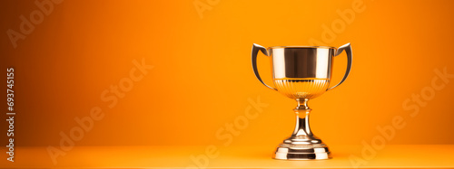 Classic gold trophy cup displayed on orange backdrop. Achievement and recognition theme. Generative AI