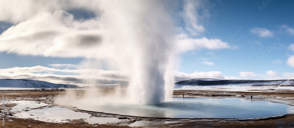 Smoke emitting from Strokkur geyser amidst landscape. Beautiful eruption from land against blue sky.