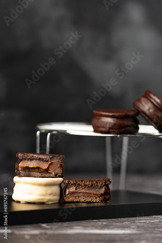 Alfajores de chocolate negro y blanco rellenos de dulce de leche sobre fondo oscuro. photo