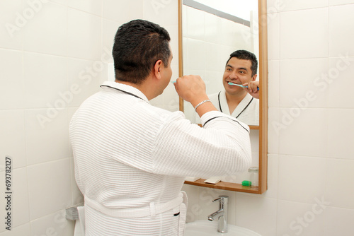 Bilde på lerret Dark-skinned 40-year-old Latin man brushes his teeth in front of the bathroom mi