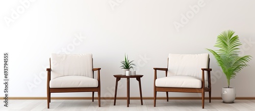 Waiting room furnished with two armchairs and white wall behind. photo