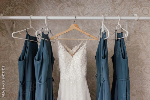 Wedding Dress hanging in closet with blue bridesmaids dresses