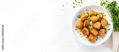 Panko chicken bites in white bowl on white table with parsley, cutlery, top view, empty space.