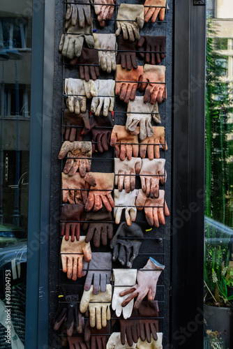 Many used dirty brown cloves displayed on a black wall