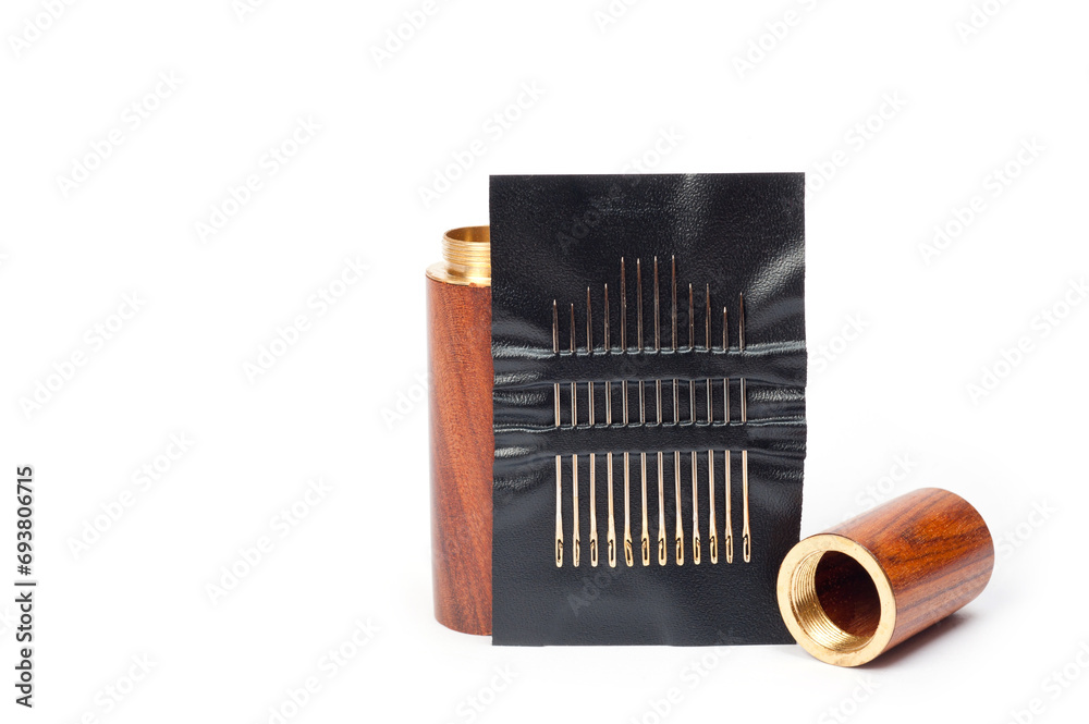 Metal sewing needles for hand sewing on a faux leather base and a container for storing them. Metal sewing needles for hand sewing on a faux leather base and a container for storing them.