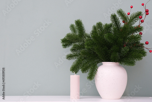 Christmas home interior - fir branshes in ceramic vase and candle on green background. photo