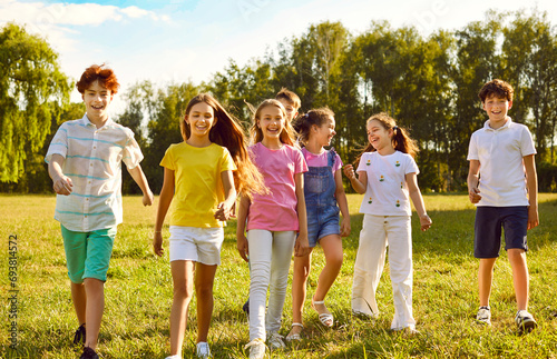Happy children friends standing together outdoors, having fun and smiling in park on holidays enjoying spending time in summer camp. Portrait of a kids walking in natureand having weekend activity photo