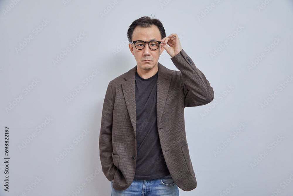 Handsome Asian businessman in suit with eyeglass smile and look at camera on grey background. Handsome Asian businessman in suit with eyeglass smile and look at camera on grey background.