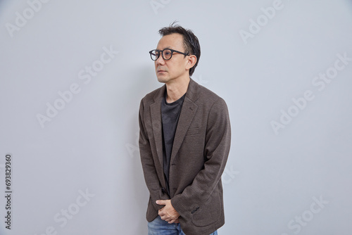 Asian businessman in suit having benign prostatic hyperplasia, urinary tract infection, and polycystic ovary syndrome on grey background.