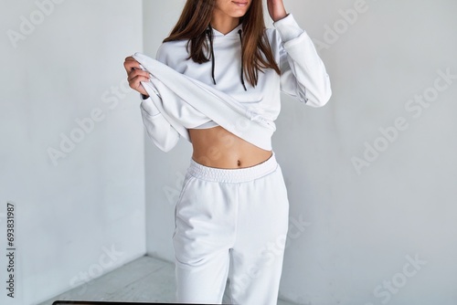 Horizontal isolated photo of an unrecognizable brunette girl wearing a white hoodie. Mock-up of a hooded sweatshirt worn by a girl in the studio. Streetwear apparel print design template. photo