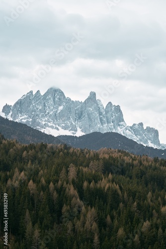 A scenic view of the Dolomites mountains in Italy with green trees and blue sky