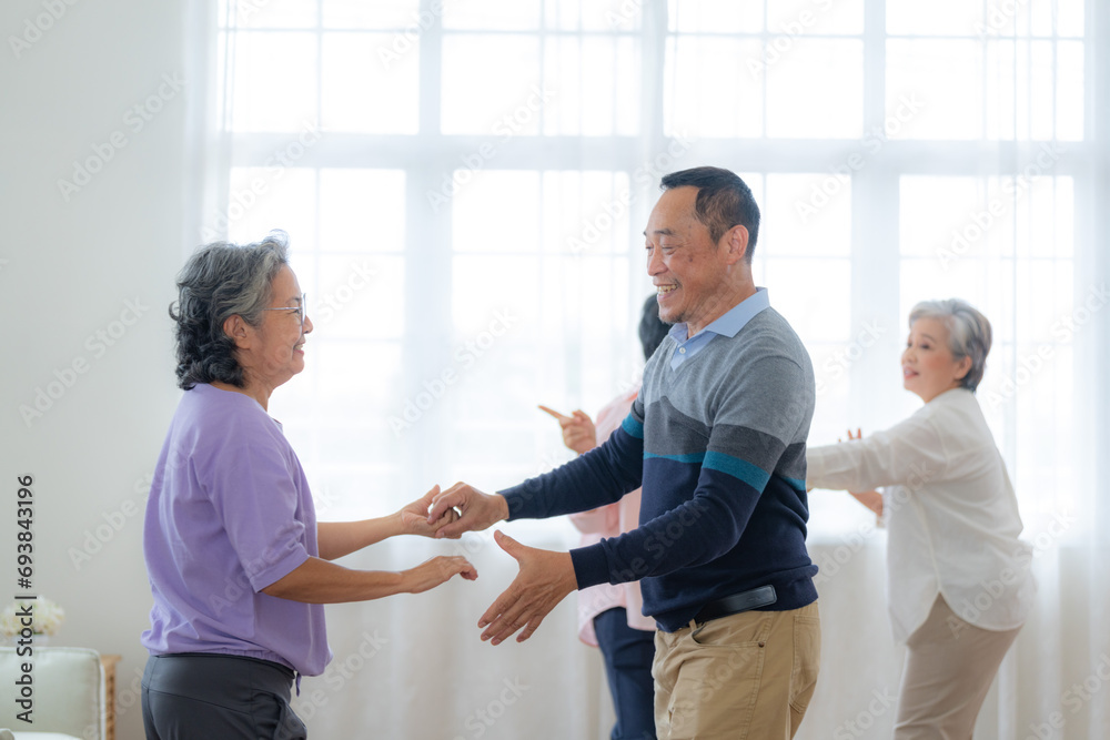 Asian Older male and females people dance with their partners on a dancing floor in living space. Happy older couple performing get exercise. Joyful carefree retired senior friends enjoying relaxation Asian Older male and females people dance with their partners on a dancing floor in living space. Happy older couple performing get exercise. Joyful carefree retired senior friends enjoying relaxation