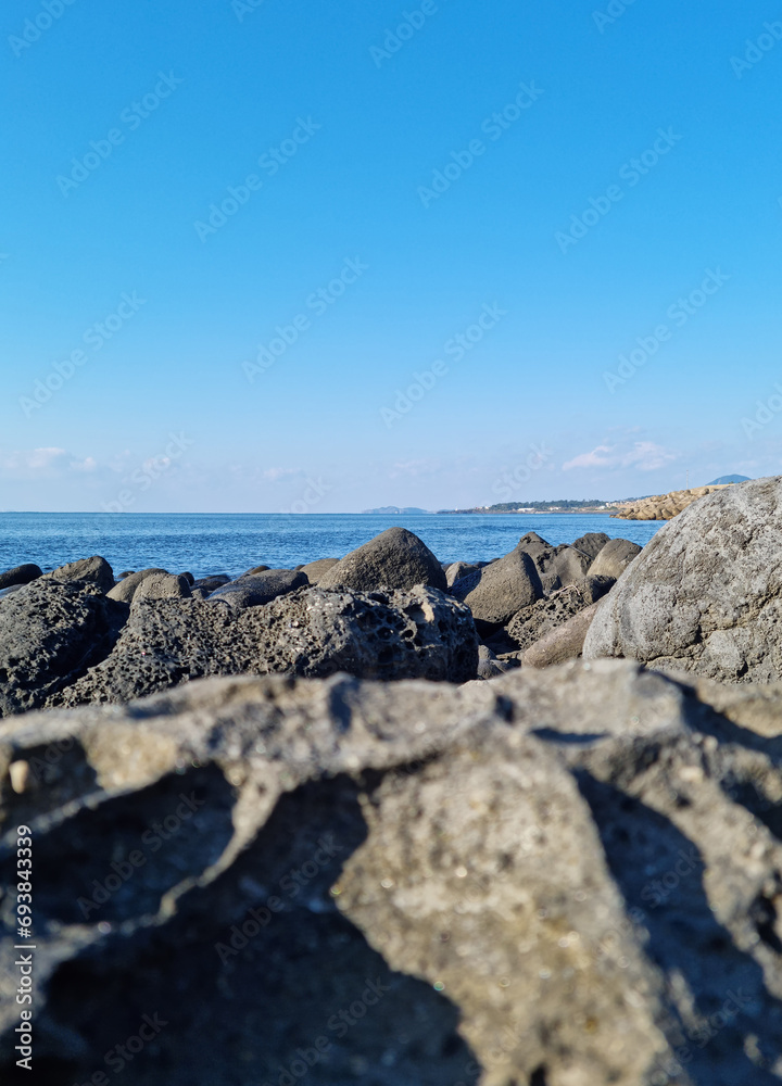 Jeju sea with blue sky and basalt rocks.