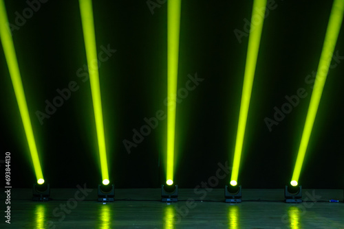 Row of neon green spotlights against black wall in conference hall