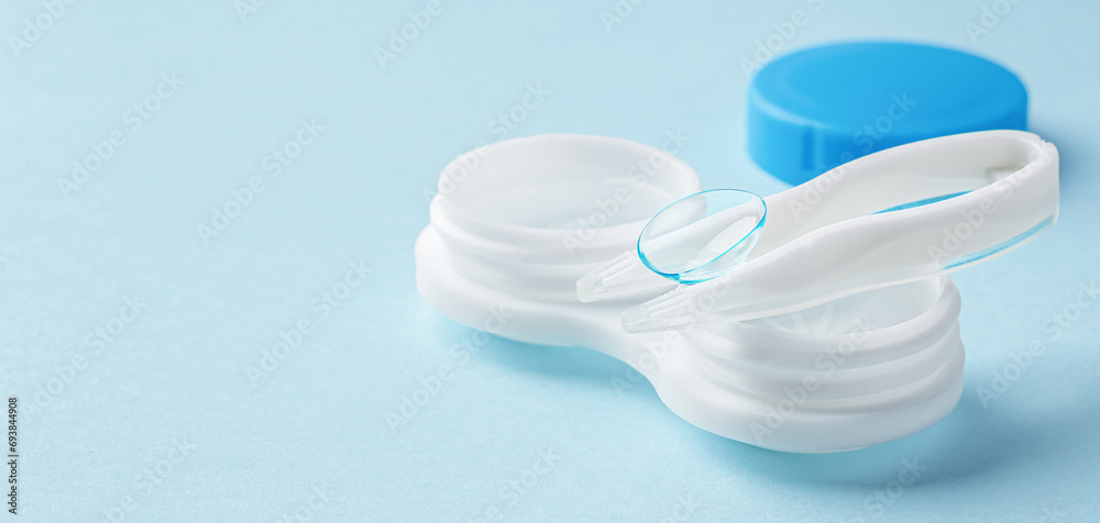 Contact lens on tweezer with container on light blue background Contact lens on tweezer with container on light blue background